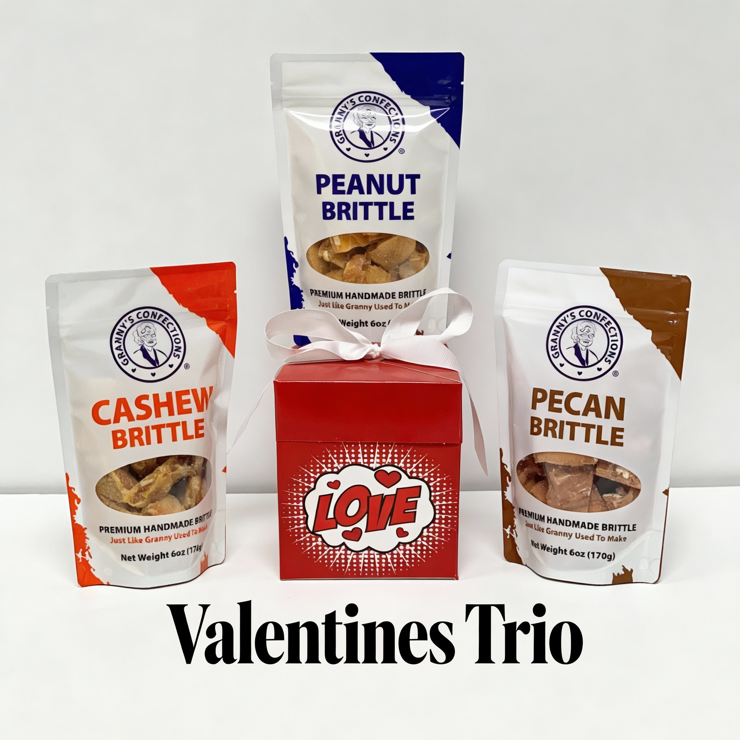 Three bags of brittle and a red 'LOVE' box on a white background with 'Valentines Trio' text. Peanut, cashew, pecan