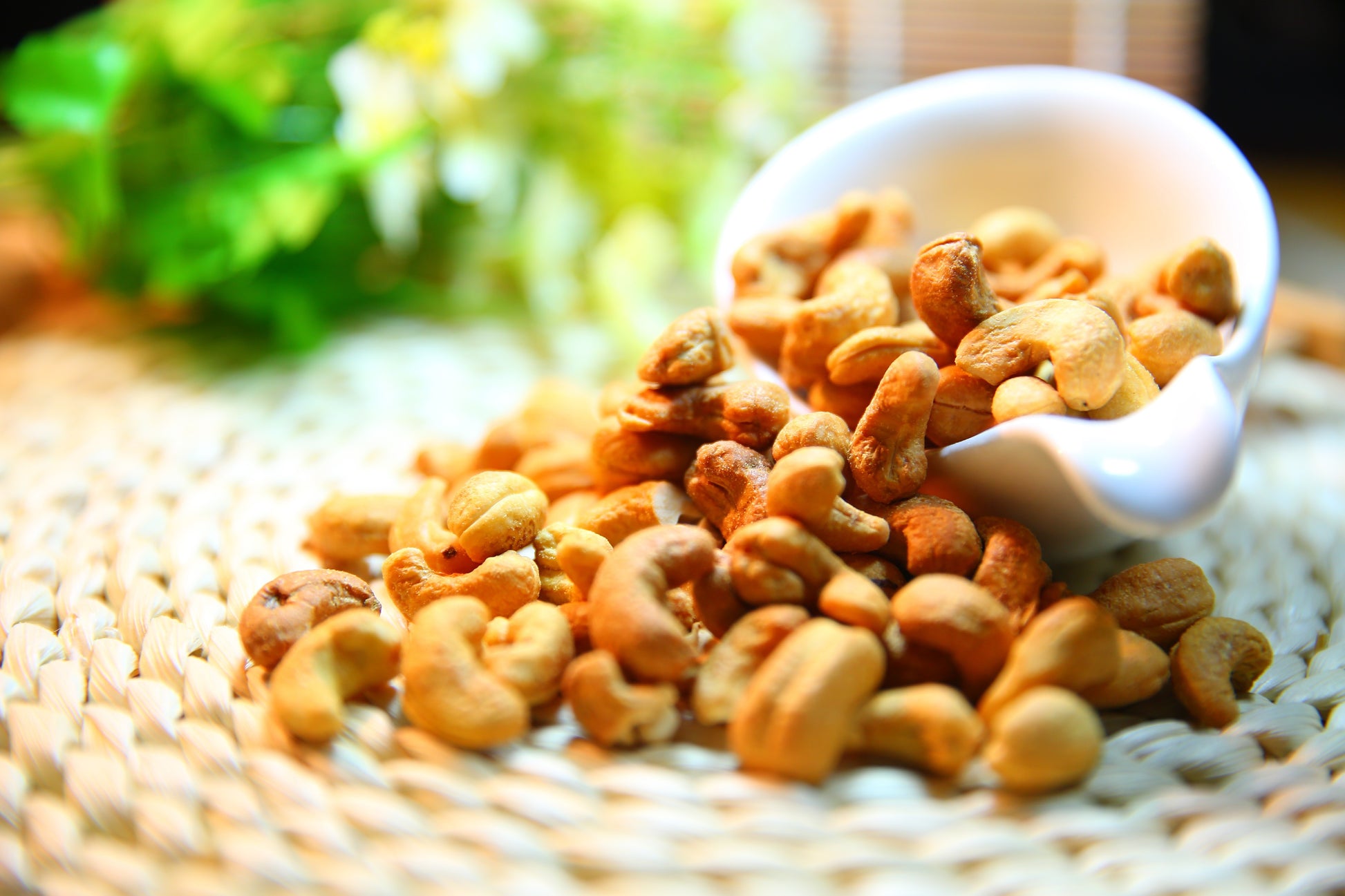 Cashews on a woven mat with a blurred natural background